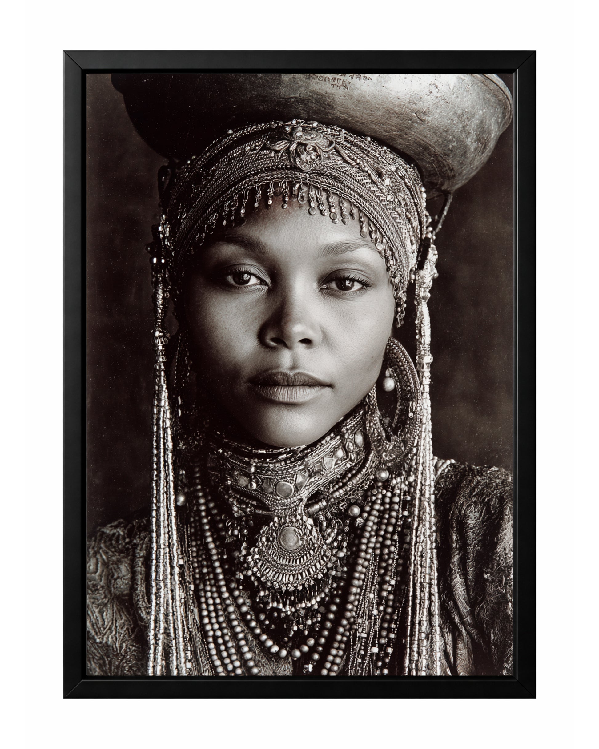Monochrome African-inspired woman portrait with ornate head covering, layered jewelry, and vessel above her head.