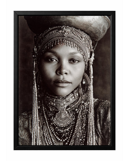 Monochrome African-inspired woman portrait with ornate head covering, layered jewelry, and vessel above her head.