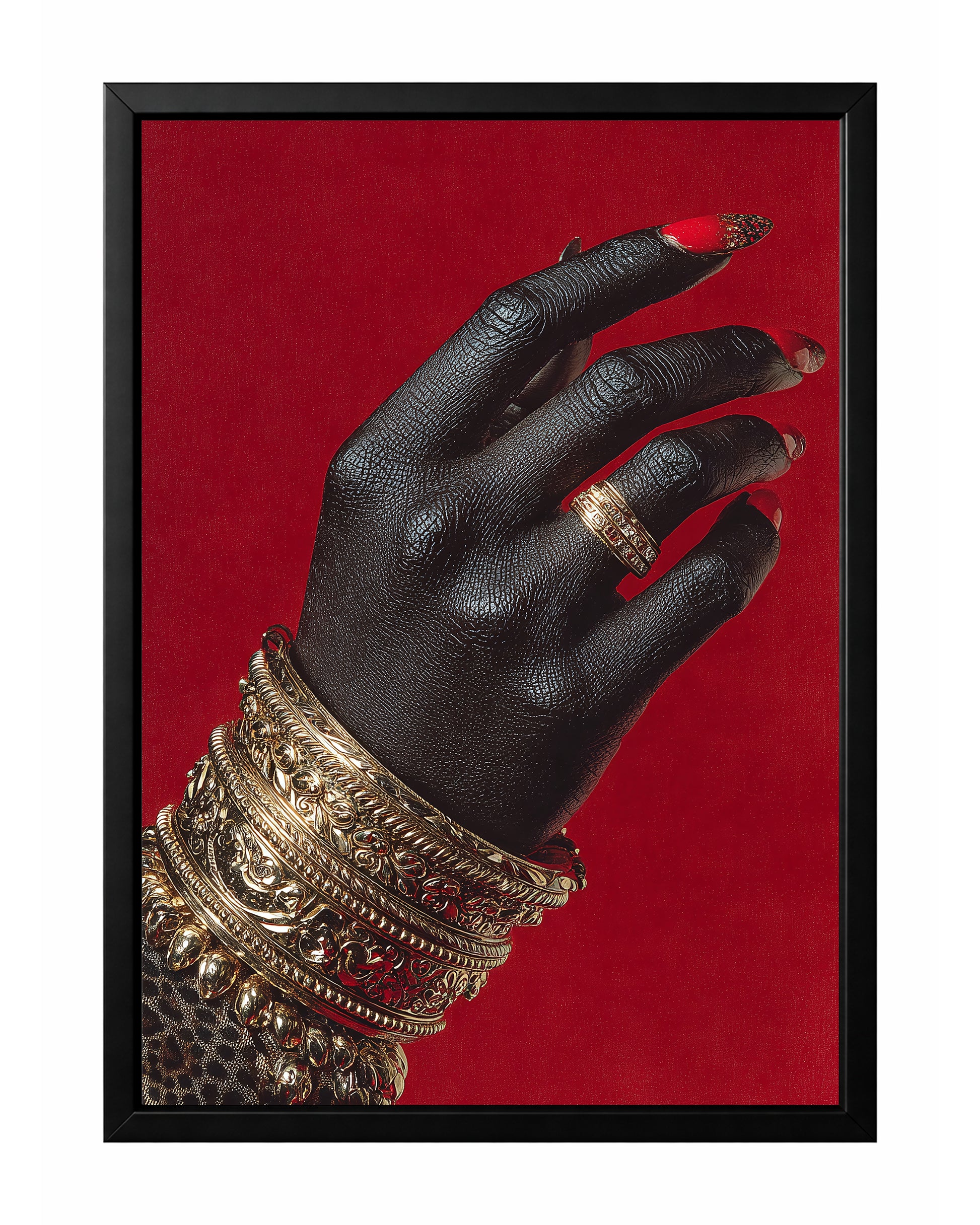 Black hand wall art with stacked ornate gold bangles, a gold ring, and glossy red nails against a vivid red background