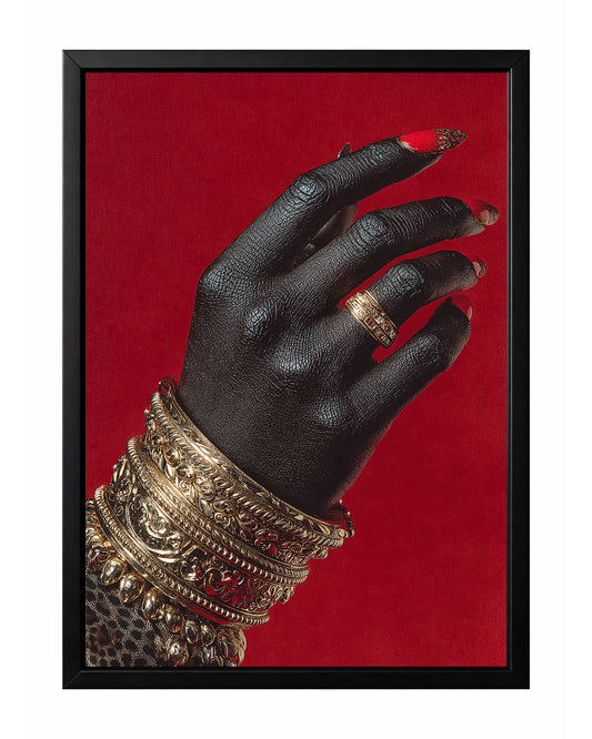 Black hand wall art with stacked ornate gold bangles, a gold ring, and glossy red nails against a vivid red background